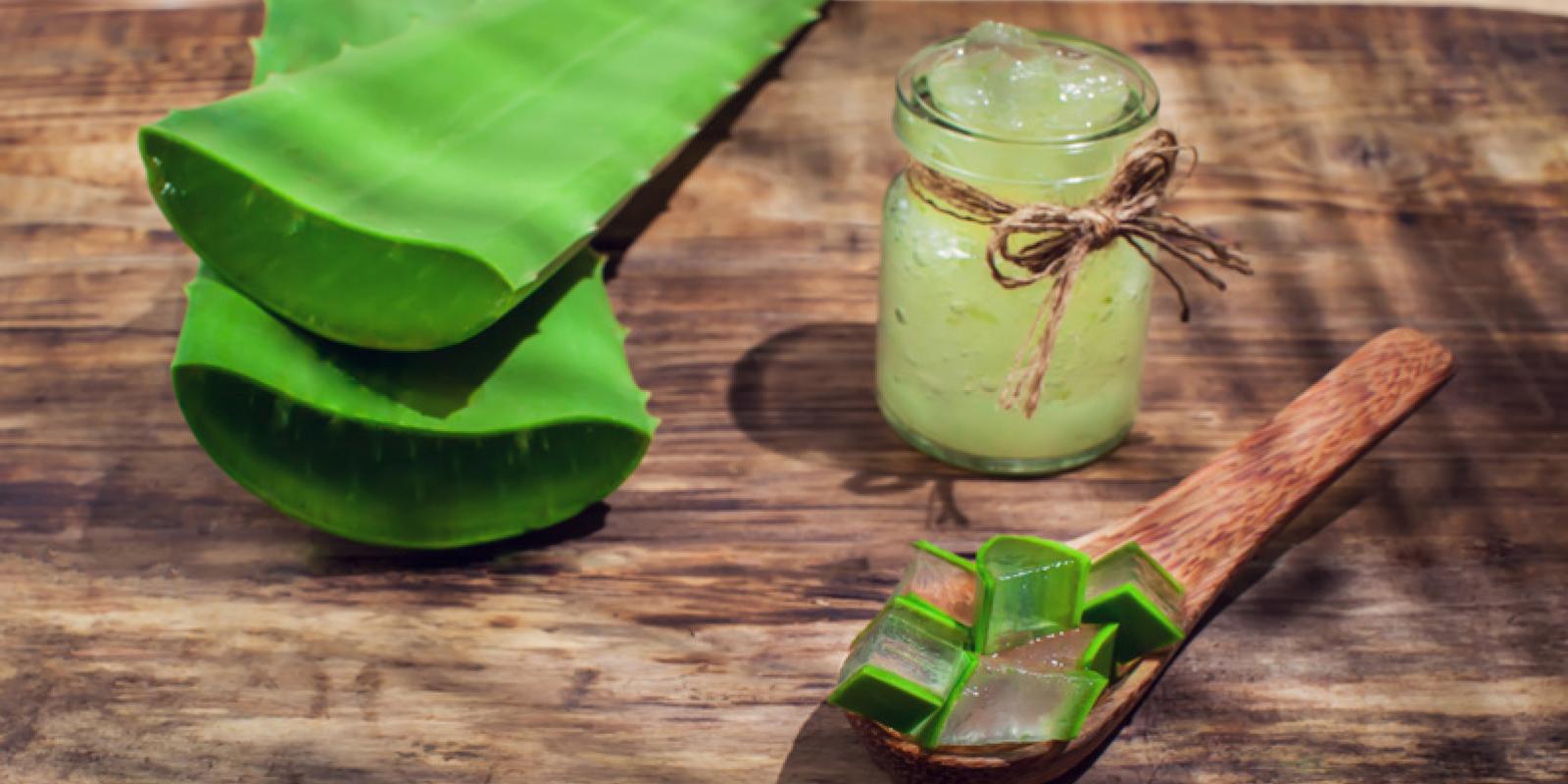 Aloe vera leaf, gel and cut pieces on a wooden background